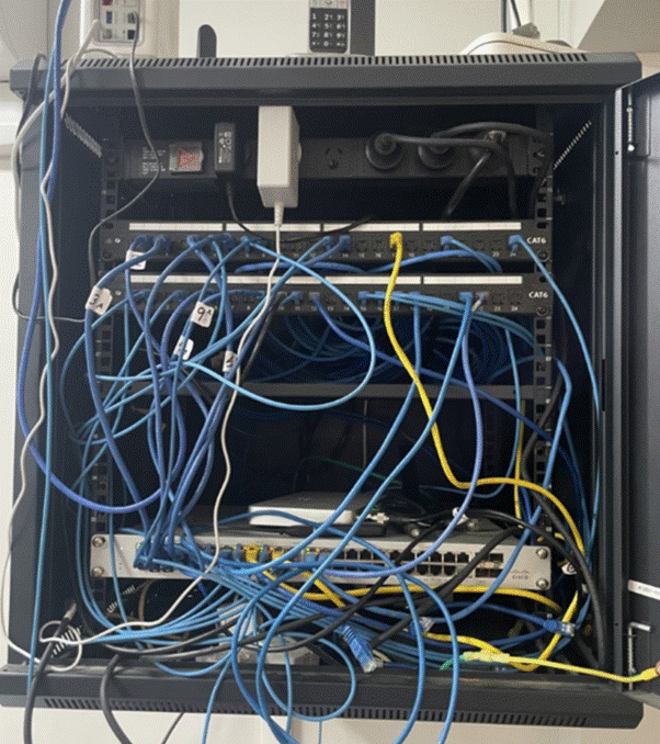 Before — Perth warehouse data cabinet, cables tangled and unmanaged, mixed patch cords