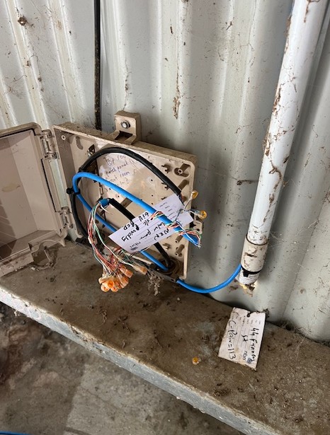 Telstra lead-in box on corrugated shed wall — cable shortfall blocking new service activation, Sydney warehouse