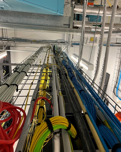 Structured cable tray runs — OS2, Cat6A blue, conduit, data centre ceiling