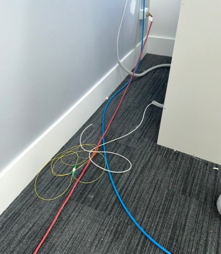 Active NBN fibre lying loose on office floor with no conduit protection — Wollongong CBD office renovation