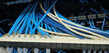 Retail patch panel — poorly terminated UTP cables hanging loose with no cable restraint or fixing